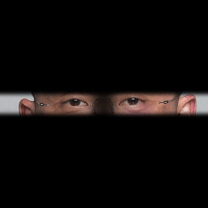 A pair of eyes visible through a narrow horizontal opening in black
